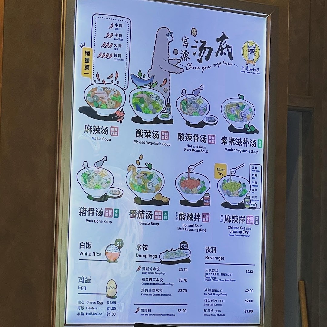 A brightly lit menu board showcasing various soup bases, dumplings, and beverages at Gong Yuan Mala Tang.