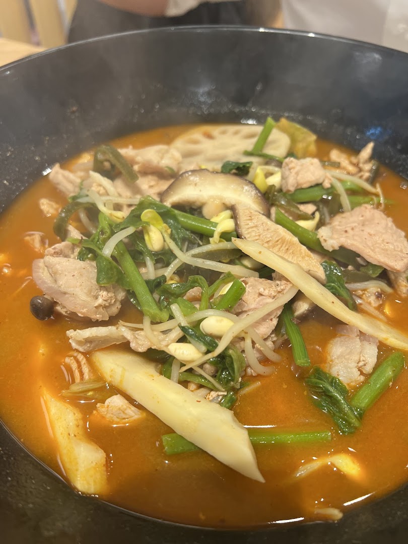 A steaming bowl of Mala Tang with various ingredients like meat, mushrooms, and vegetables.