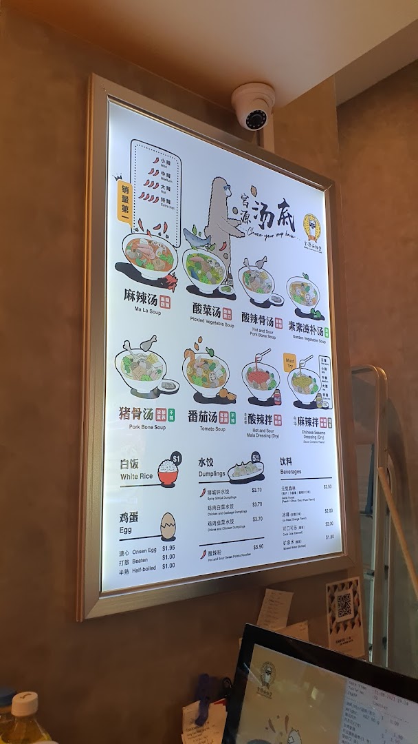 A brightly lit menu board showcasing various soup bases, dumplings, and beverages at Gong Yuan Ma La Tang.