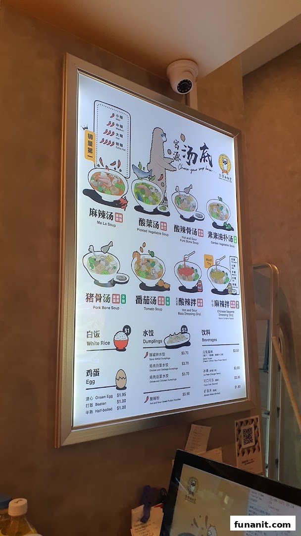 A brightly lit menu board showcasing various soup bases, dumplings, and beverages at Gong Yuan Ma La Tang.