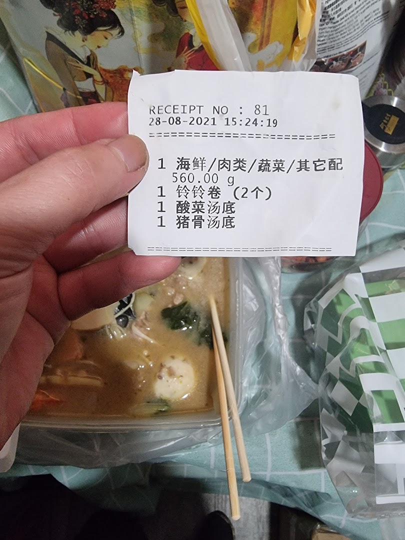 A hand holds a receipt detailing a Mala Tang order, with the customizable dish visible below.