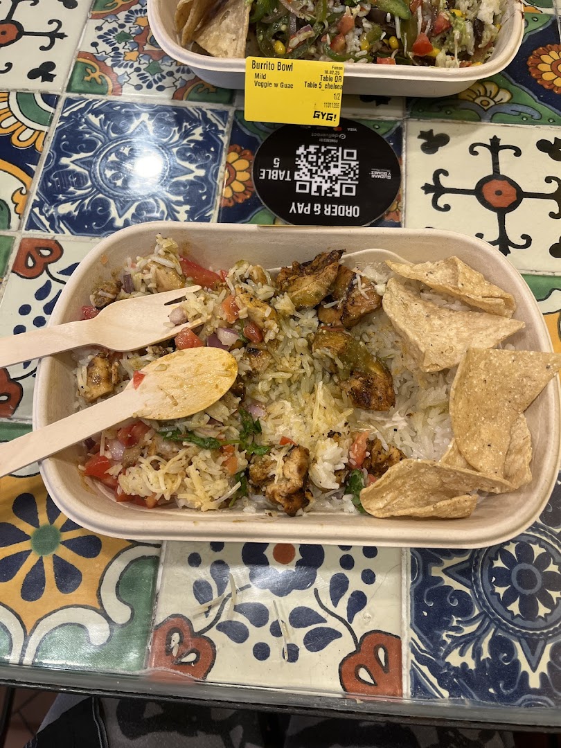 Two delicious Guzman y Gomez burrito bowls with fresh ingredients on a vibrant tiled table.
