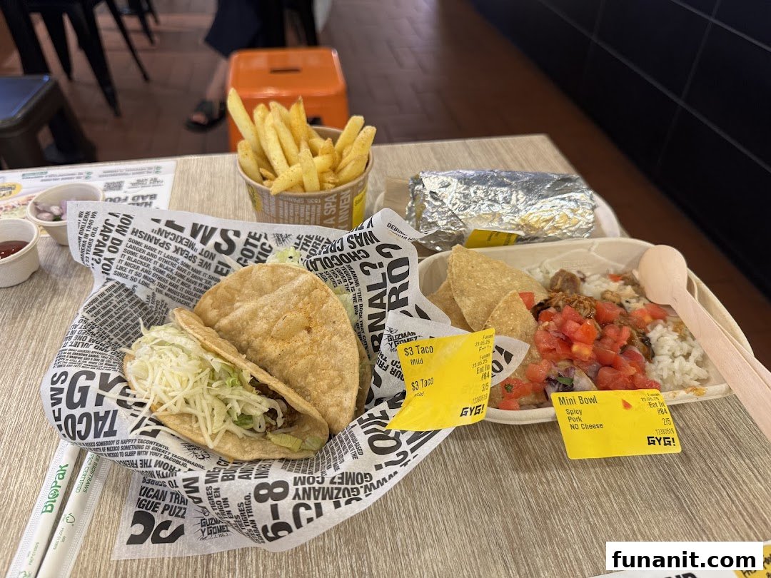 A table spread with Guzman y Gomez Mexican food, including tacos, fries, a burrito, and a mini bowl.