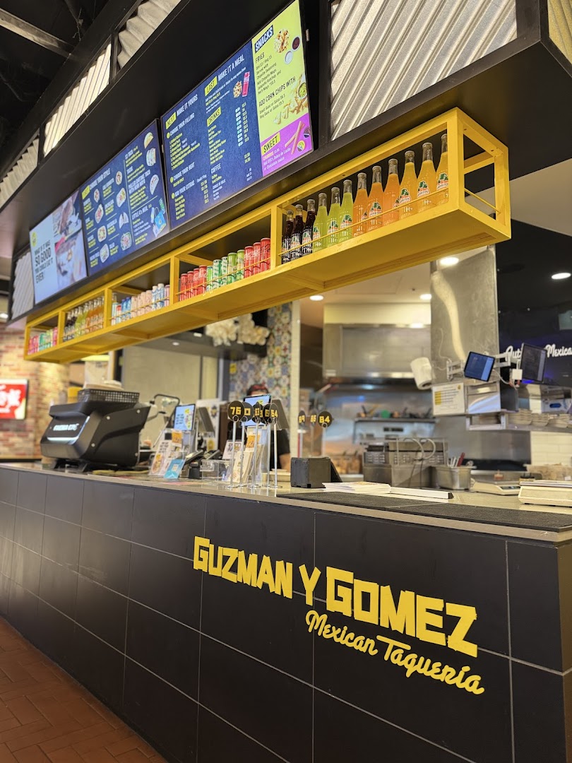 Digital menu boards displaying food and drink options at Guzman y Gomez.