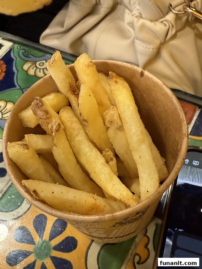 A close-up shot of a cup filled with golden, seasoned french fries from Guzman y Gomez.