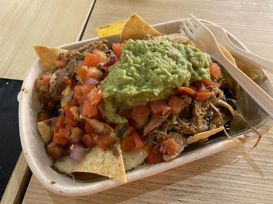 A delicious serving of loaded nachos or fries with pulled meat, fresh salsa, and guacamole.