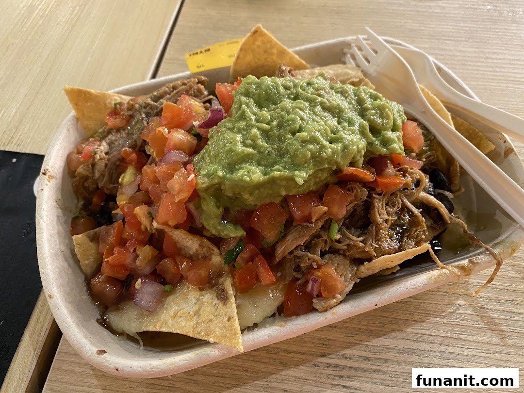 A delicious serving of loaded nachos or fries with pulled meat, fresh salsa, and guacamole.