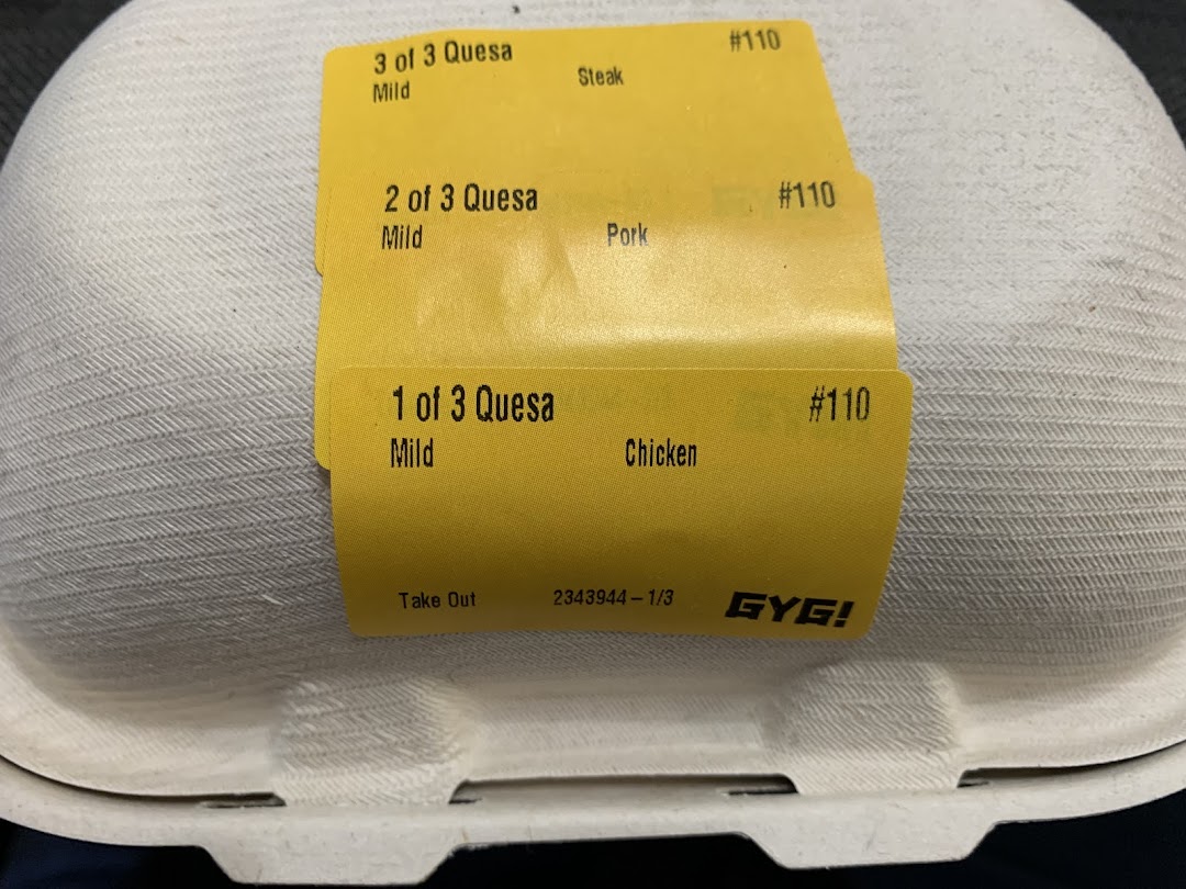 A close-up of a Guzman y Gomez takeaway container with order labels for quesadillas.