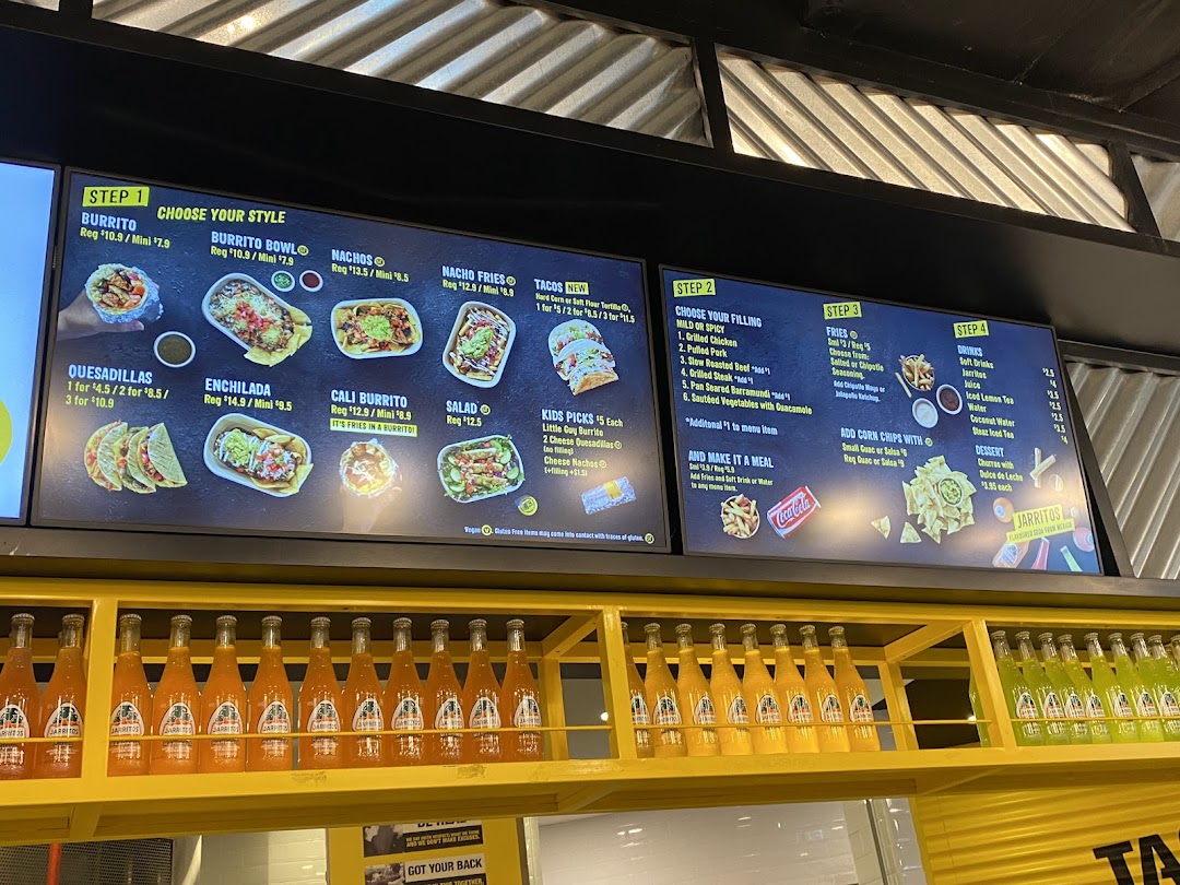 A digital menu board displaying various Mexican food options, drinks, and pricing at Guzman y Gomez.