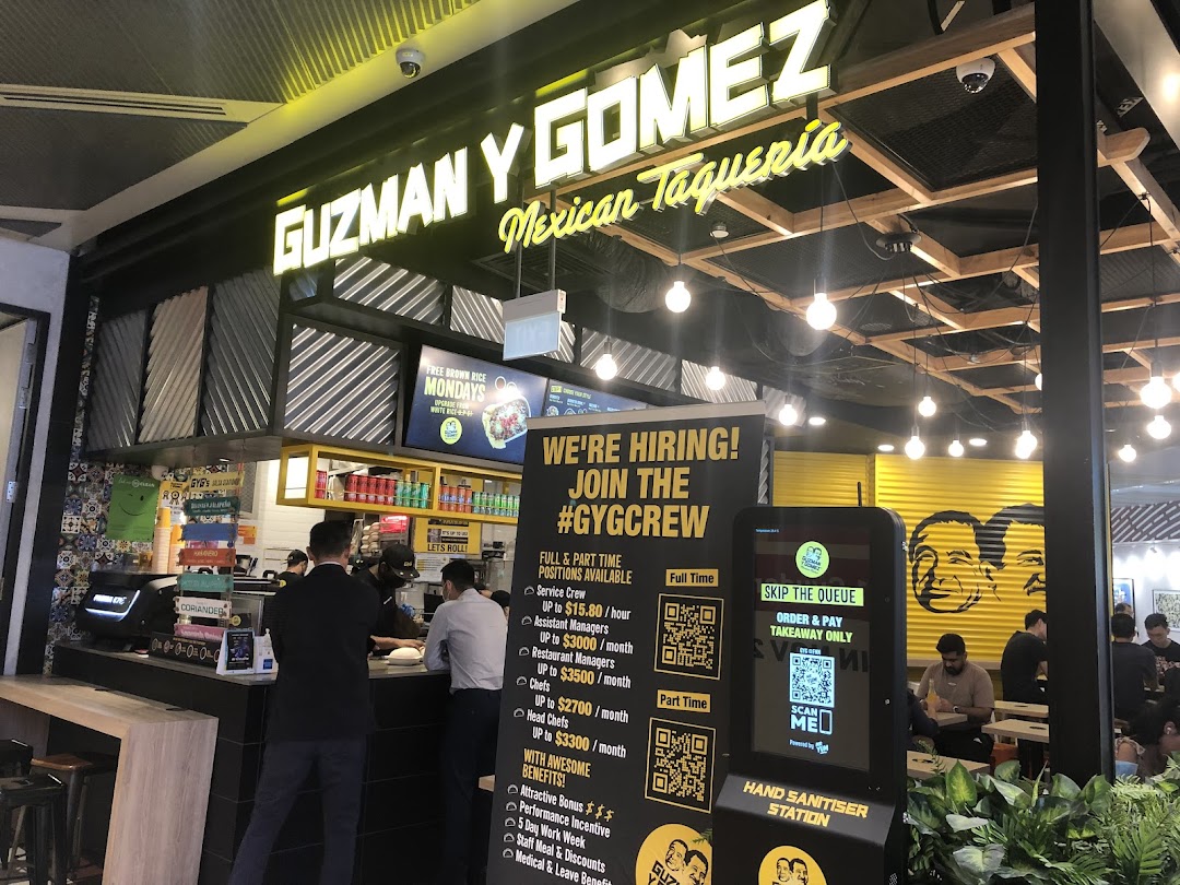 A vibrant interior view of Guzman y Gomez, showcasing the counter, dining area, and hiring information.