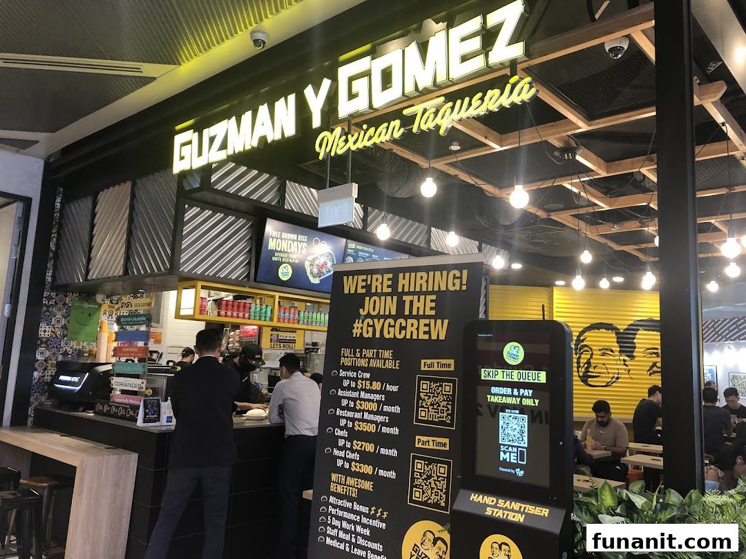 A vibrant interior view of Guzman y Gomez, showcasing the counter, dining area, and hiring information.