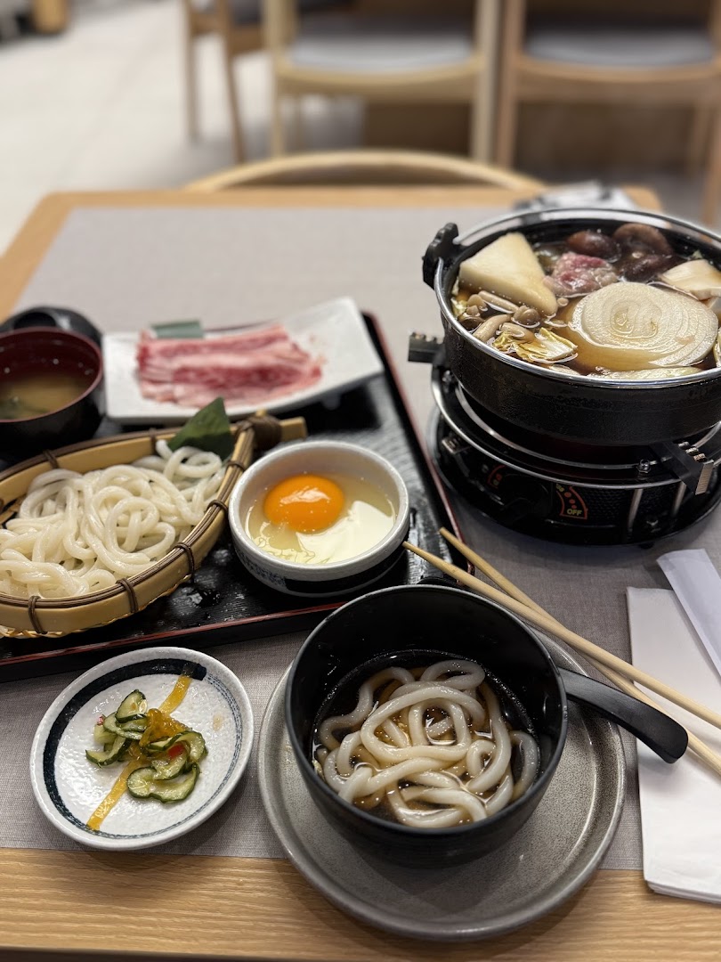 A delicious Japanese sukiyaki hotpot set with raw beef, udon noodles, and a raw egg, ready for cooking.