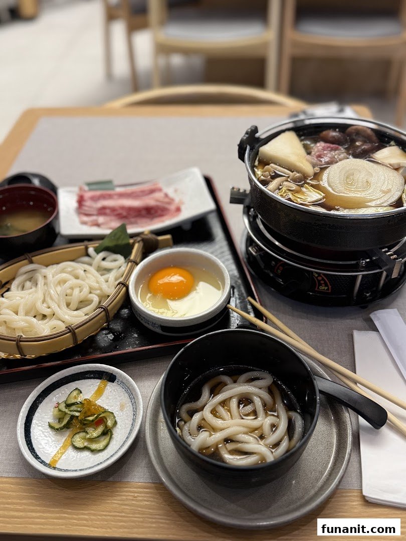 A delicious Japanese sukiyaki hotpot set with raw beef, udon noodles, and a raw egg, ready for cooking.