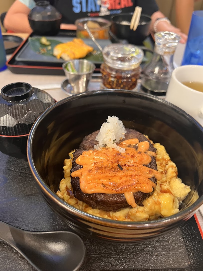 A close-up of a Japanese hamburger steak bowl with eggs and sauce, served on a table at GyoGyo.