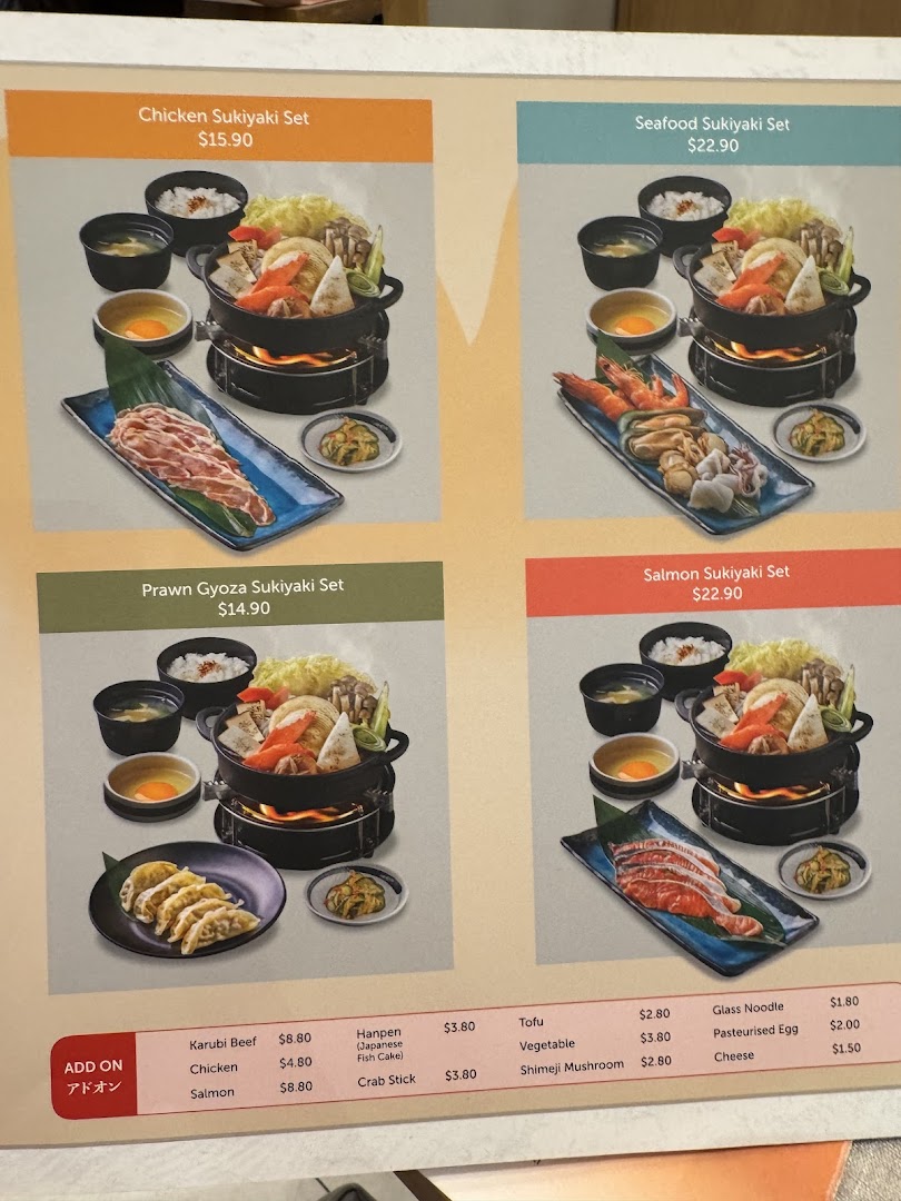 A menu board displaying various Japanese sukiyaki sets and add-on options with prices.
