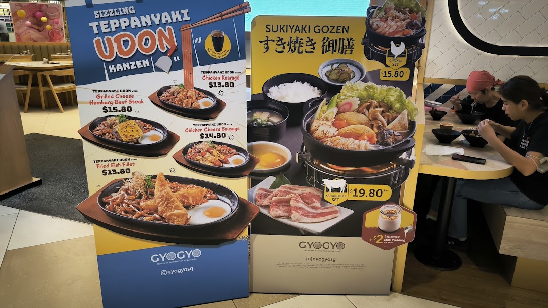 Promotional standees showcasing GyoGyo's Teppanyaki Udon and Sukiyaki Gozen menu items with prices.