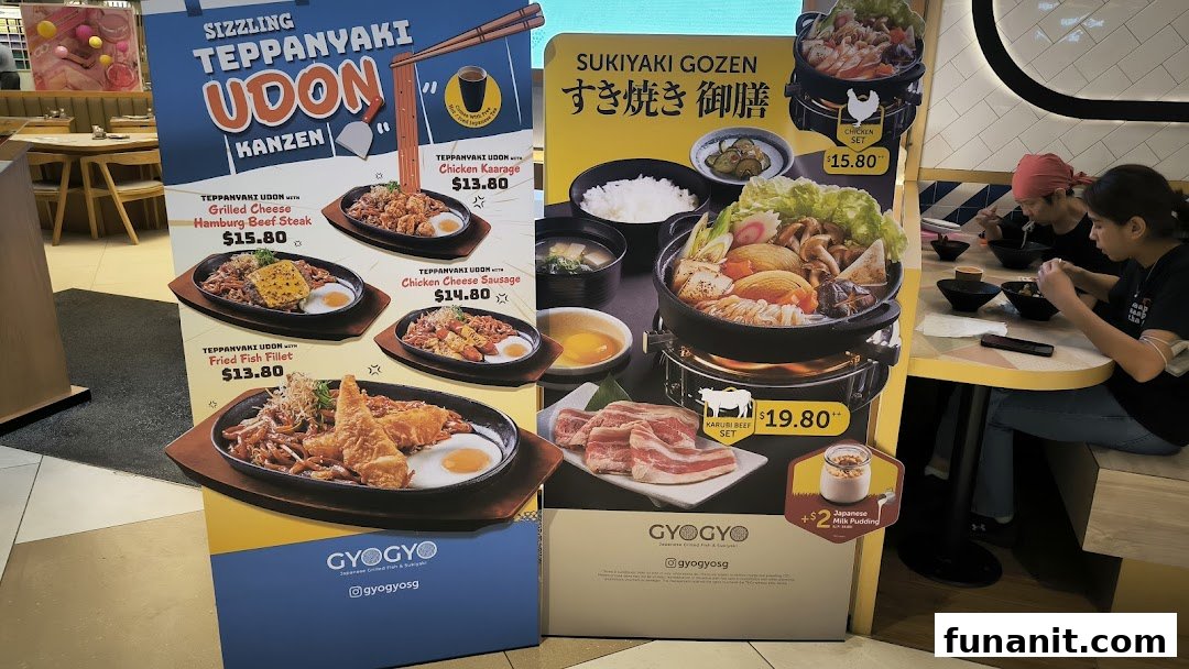 Promotional standees showcasing GyoGyo's Teppanyaki Udon and Sukiyaki Gozen menu items with prices.
