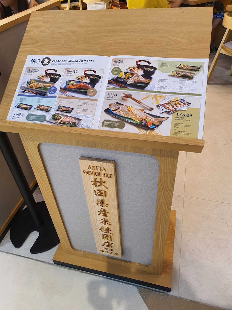 A menu stand showcasing various Japanese grilled fish sets with different cooking styles and prices.