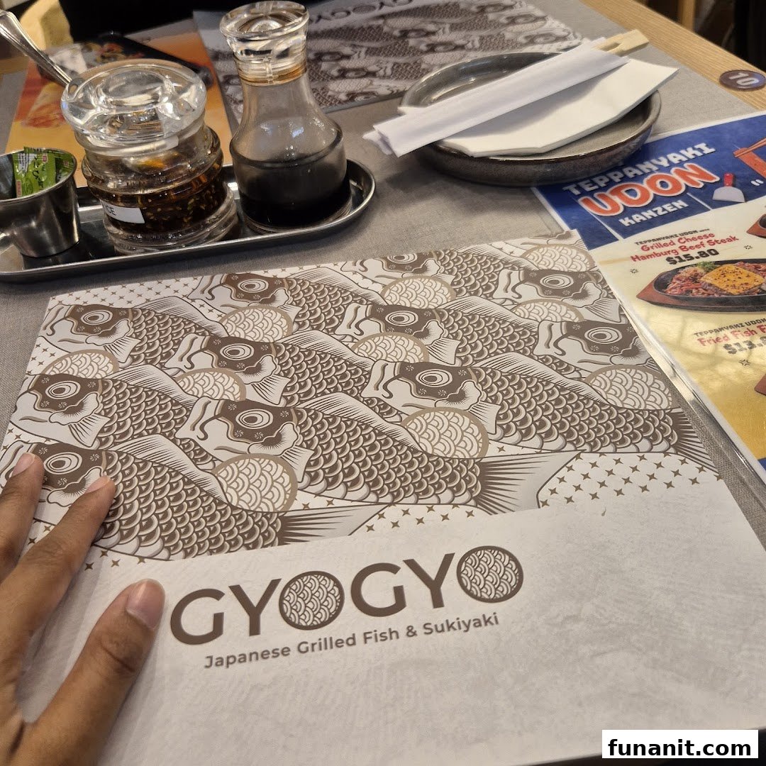 A close-up of a table setting at GyoGyo, featuring a menu with Japanese grilled fish and sukiyaki options.