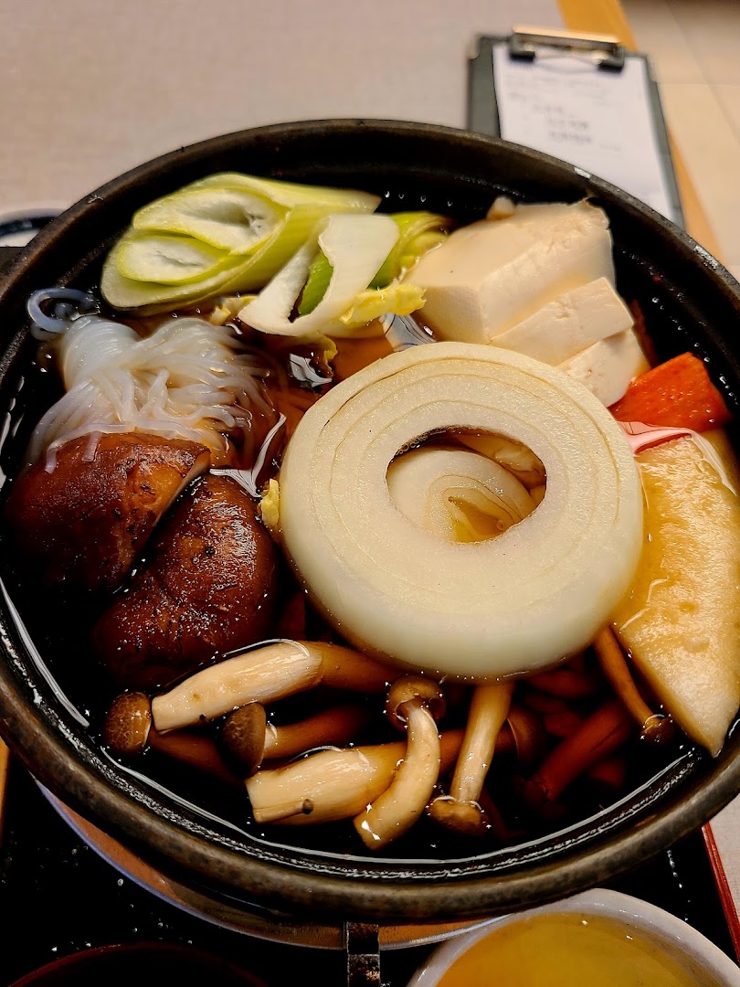 A close-up of a delicious Japanese sukiyaki pot filled with fresh vegetables, mushrooms, tofu, and noodles.