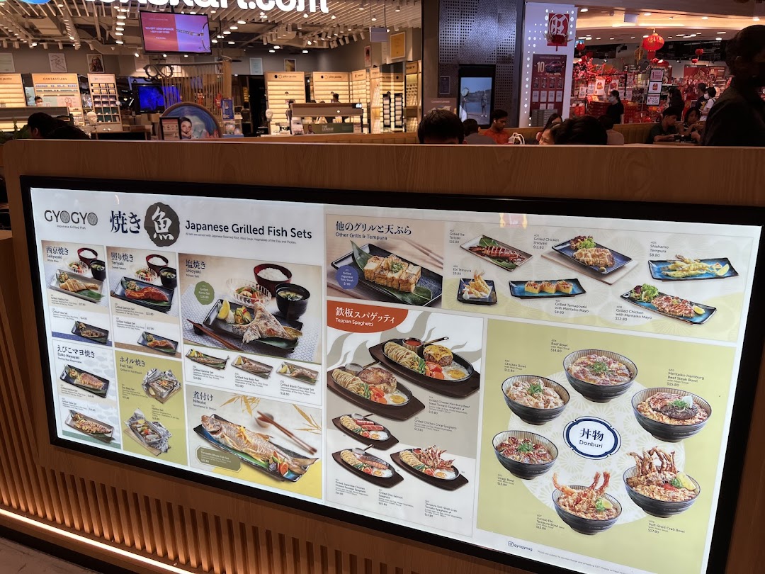 A brightly lit display menu board showcasing various Japanese grilled fish sets, donburi, and other dishes from GyoGyo.