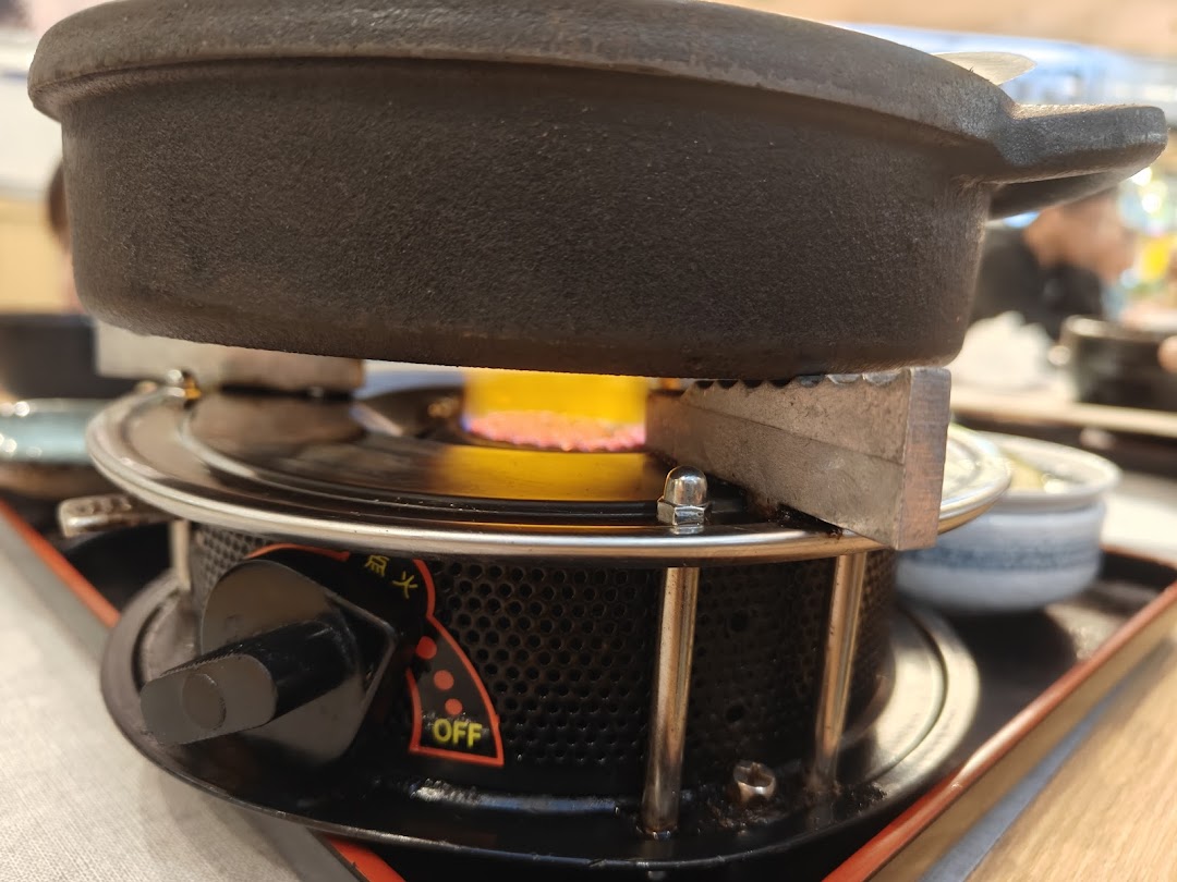 A close-up of a hot pot cooking on a portable burner with a visible flame.