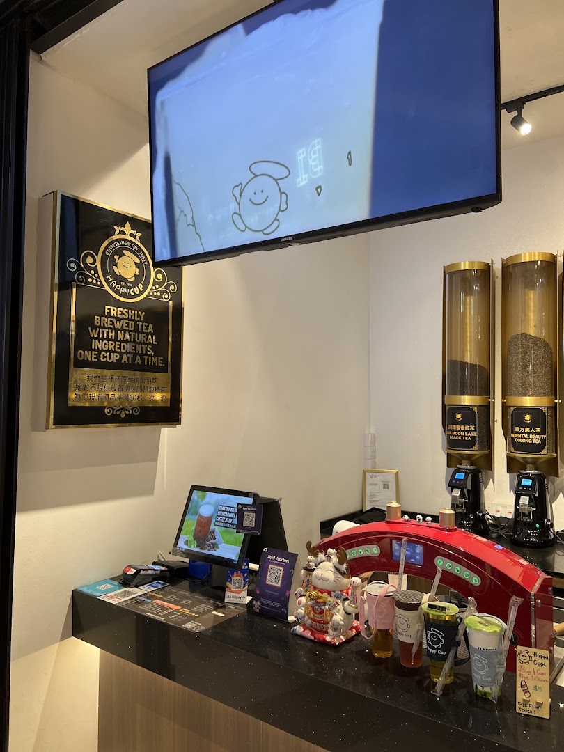 An interior view of Happy Cup's counter, showcasing fresh tea dispensers and a POS system.
