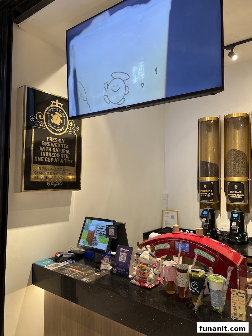 An interior view of Happy Cup's counter, showcasing fresh tea dispensers and a POS system.