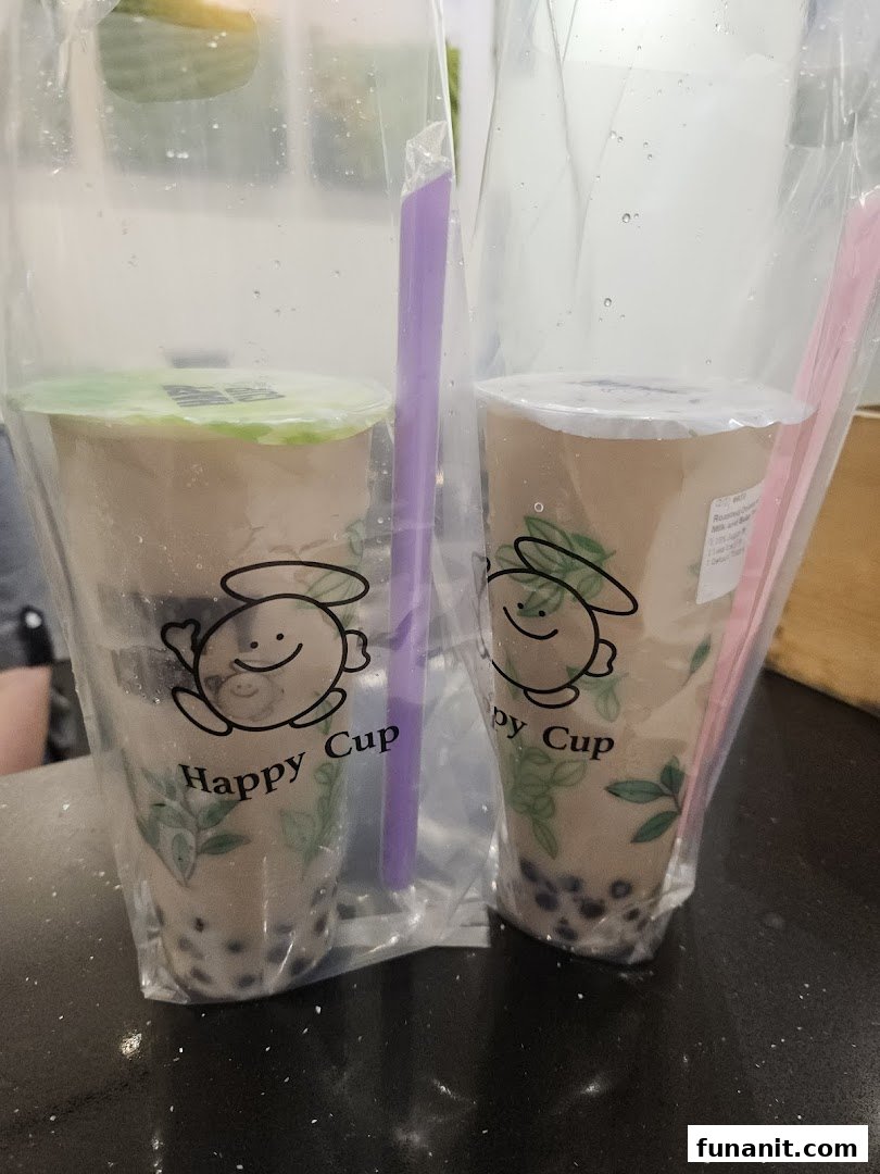Two bubble tea drinks from Happy Cup, served in clear plastic bags with straws.