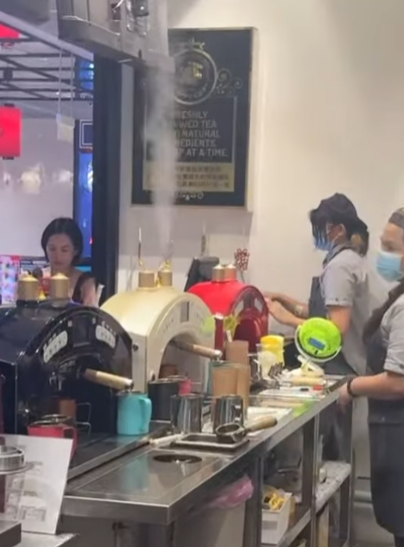 Staff prepare fresh beverages at a vibrant counter with unique tea brewing machines, showcasing the drink-making process.