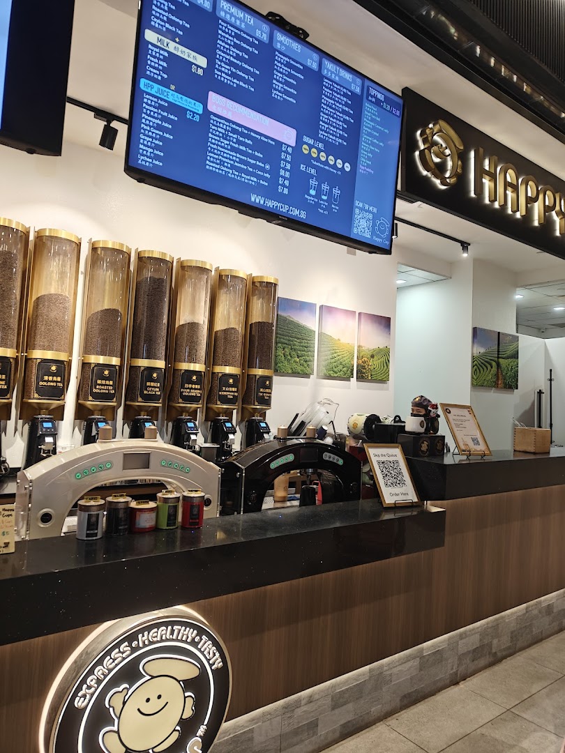 Interior view of Happy Cup Funan, featuring tea dispensers, a digital menu, and the brand logo.