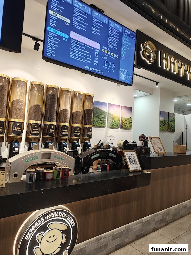 Interior view of Happy Cup Funan, featuring tea dispensers, a digital menu, and the brand logo.