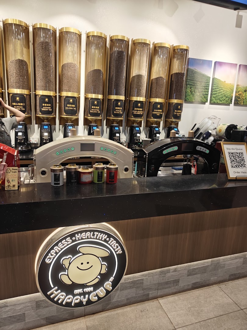 An interior shot of Happy Cup's counter, featuring large dispensers of various tea leaves and the brand's illuminated logo.