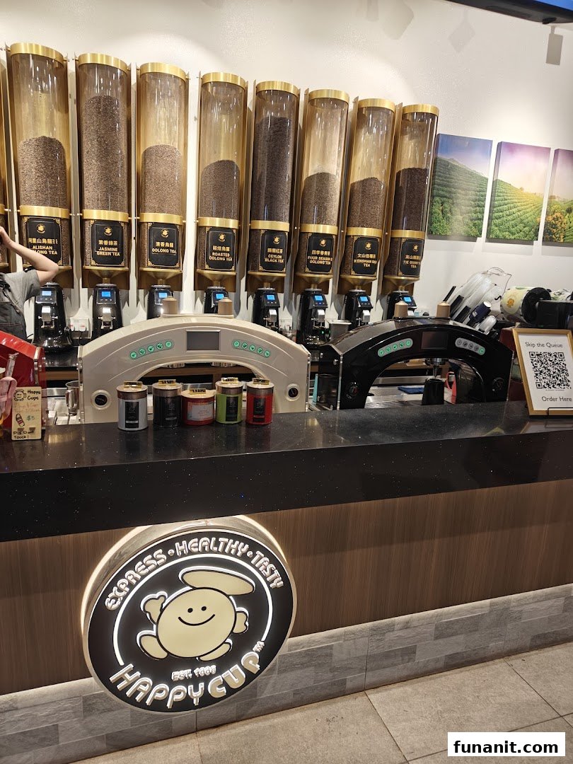 An interior shot of Happy Cup's counter, featuring large dispensers of various tea leaves and the brand's illuminated logo.