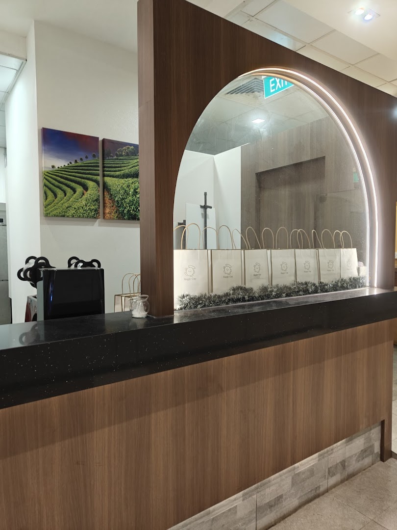 An interior view of Happy Cup Funan's counter with tea-themed artwork and branded bags.