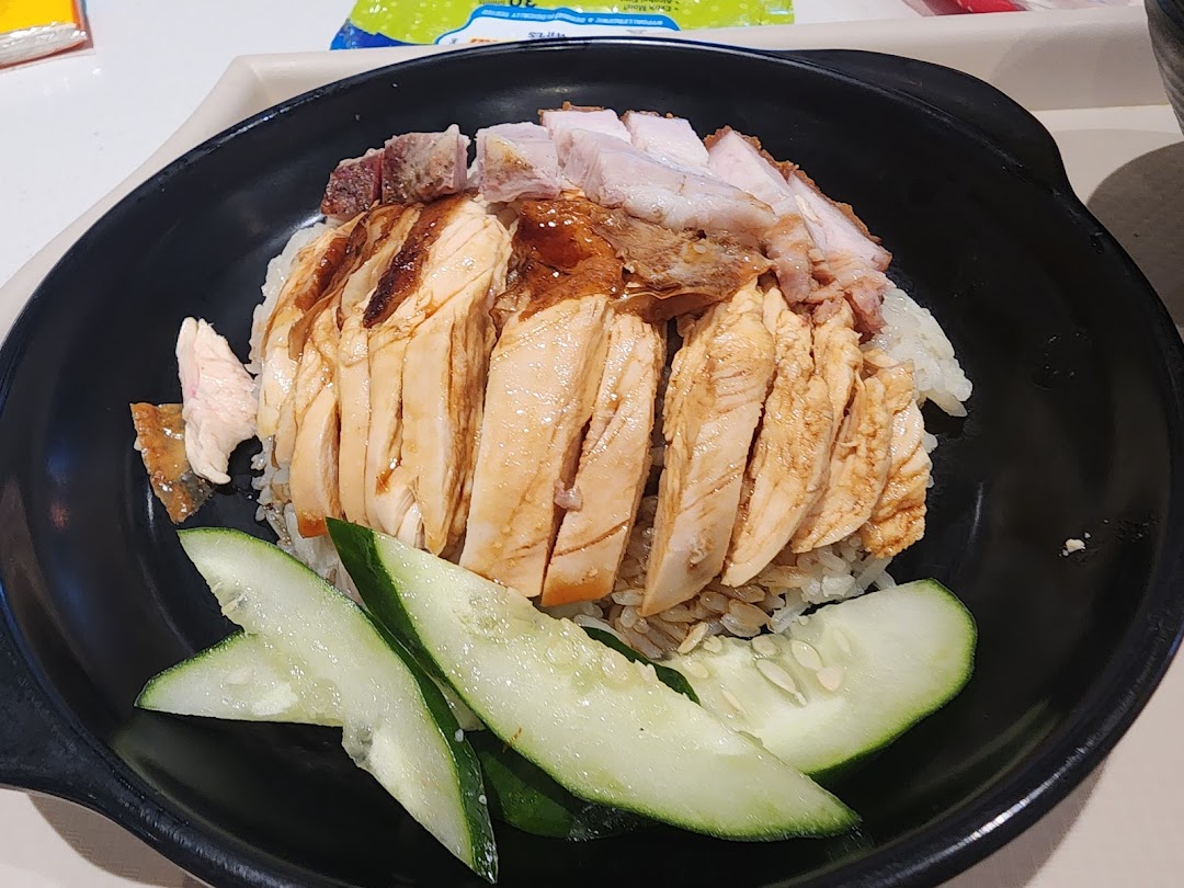 A delicious bowl of roasted chicken and pork with rice and cucumber slices.