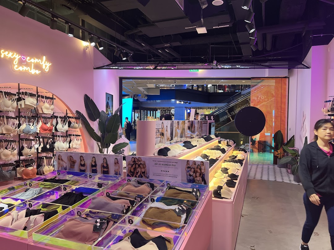 Vibrant interior of IM IN IMINXX lingerie shop showcasing bras, undergarments, and a 'sexy comfy combo' neon sign.