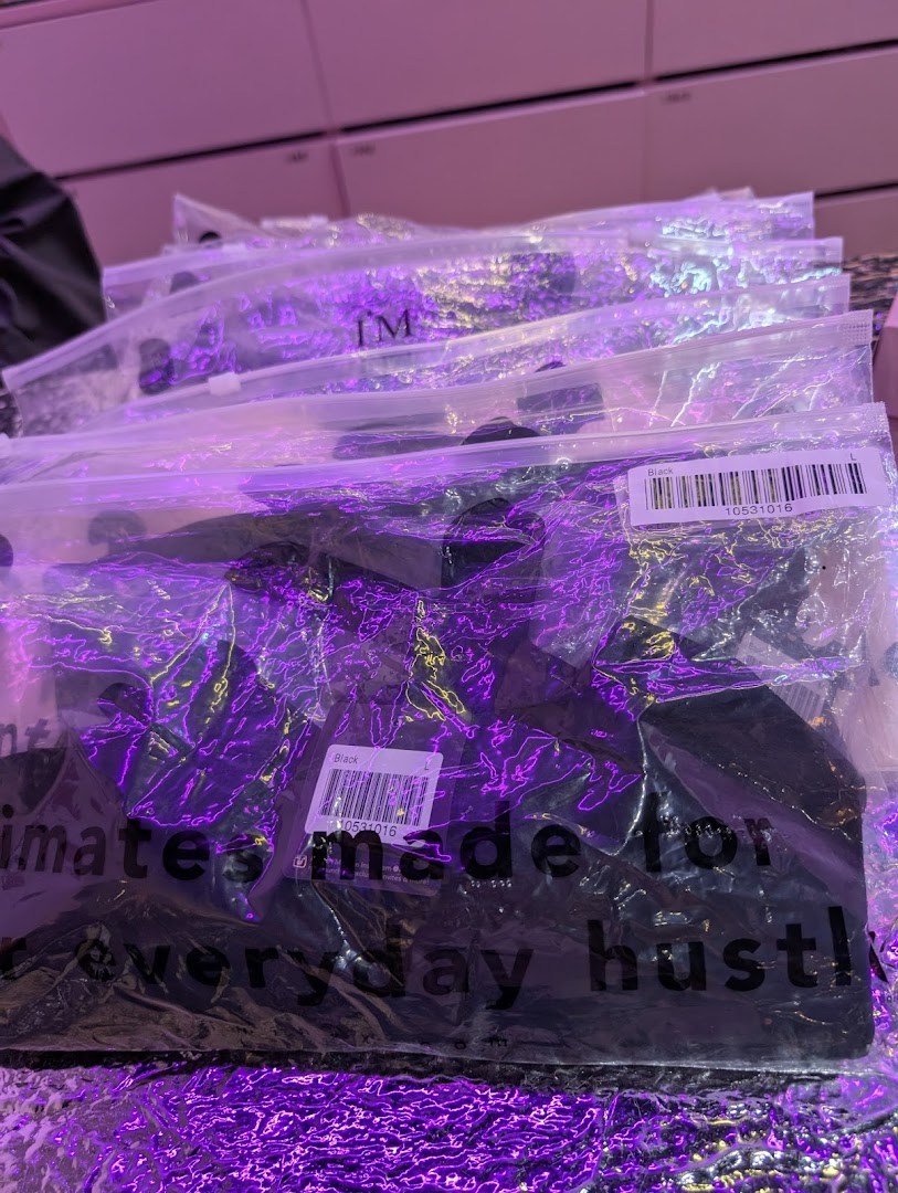 Close-up of packaged black apparel items from IM IN IMINXX, featuring 'intimates made for everyday hustle!'.