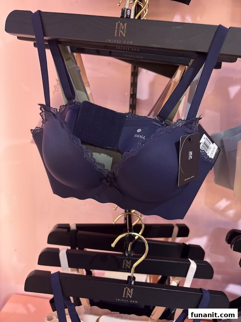 A dark blue bra with lace details displayed on a hanger in a retail store.