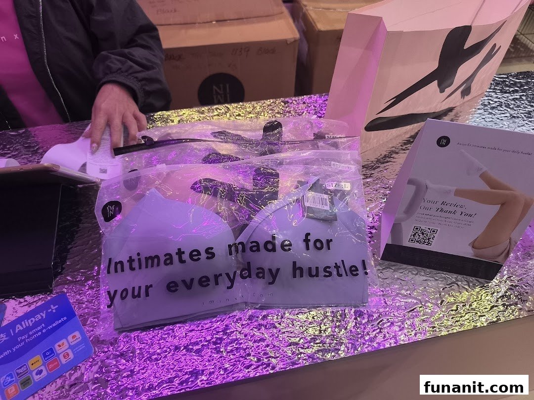 Packaged intimates from IM IN IMINXX displayed on a counter with promotional materials and a shopping bag.