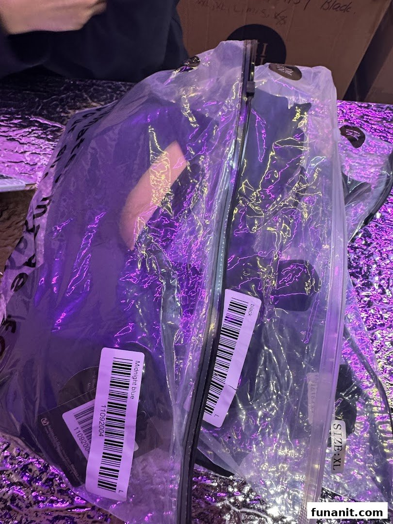 Close-up of packaged clothing items with labels, illuminated by purple light.