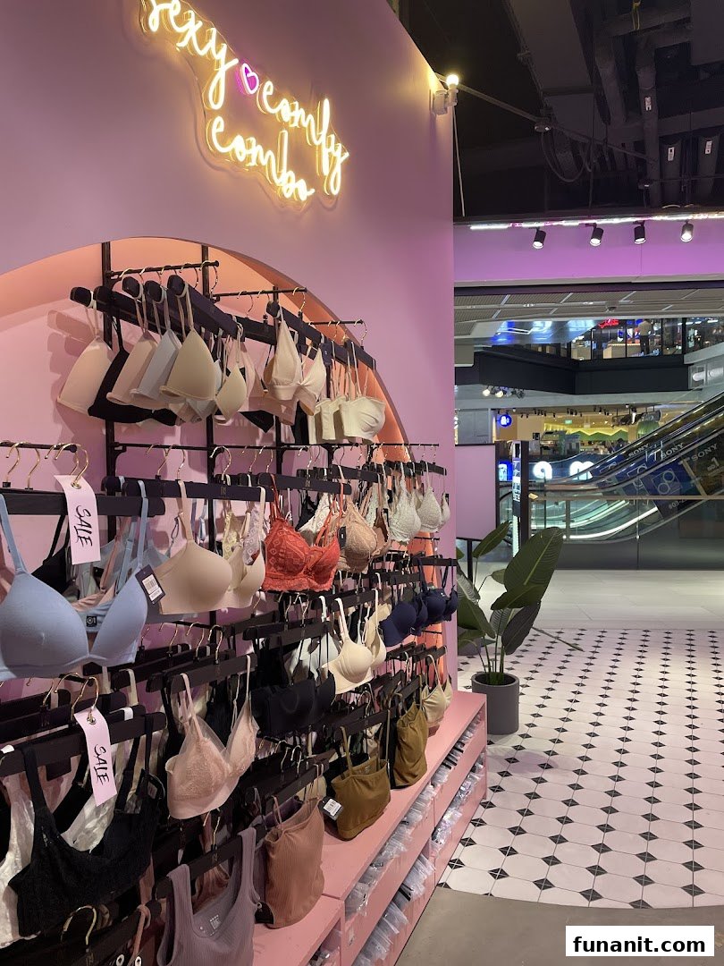 Interior view of IM IN IMINXX, a lingerie shop, showcasing bras on pink displays with a neon sign.