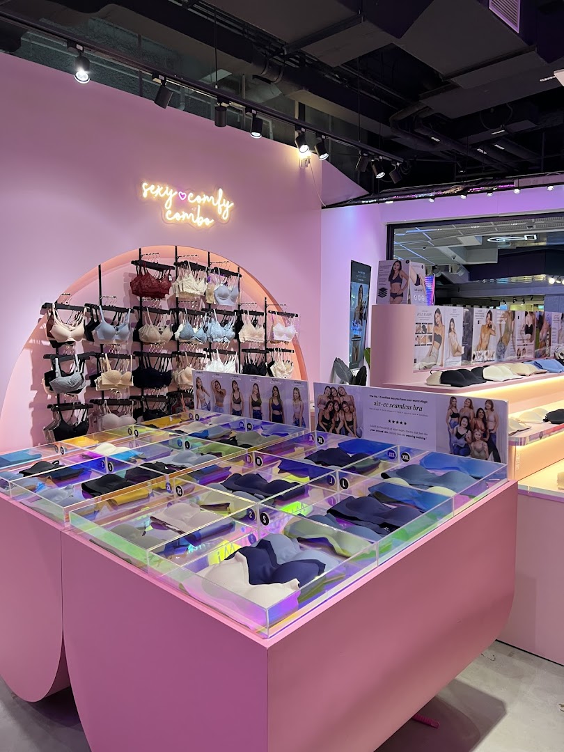 Vibrant pink lingerie shop interior showcasing bras on display racks and in organized bins.