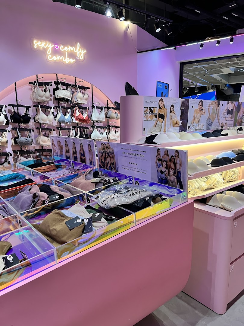 Interior view of a vibrant lingerie and apparel shop with pink decor and product displays.