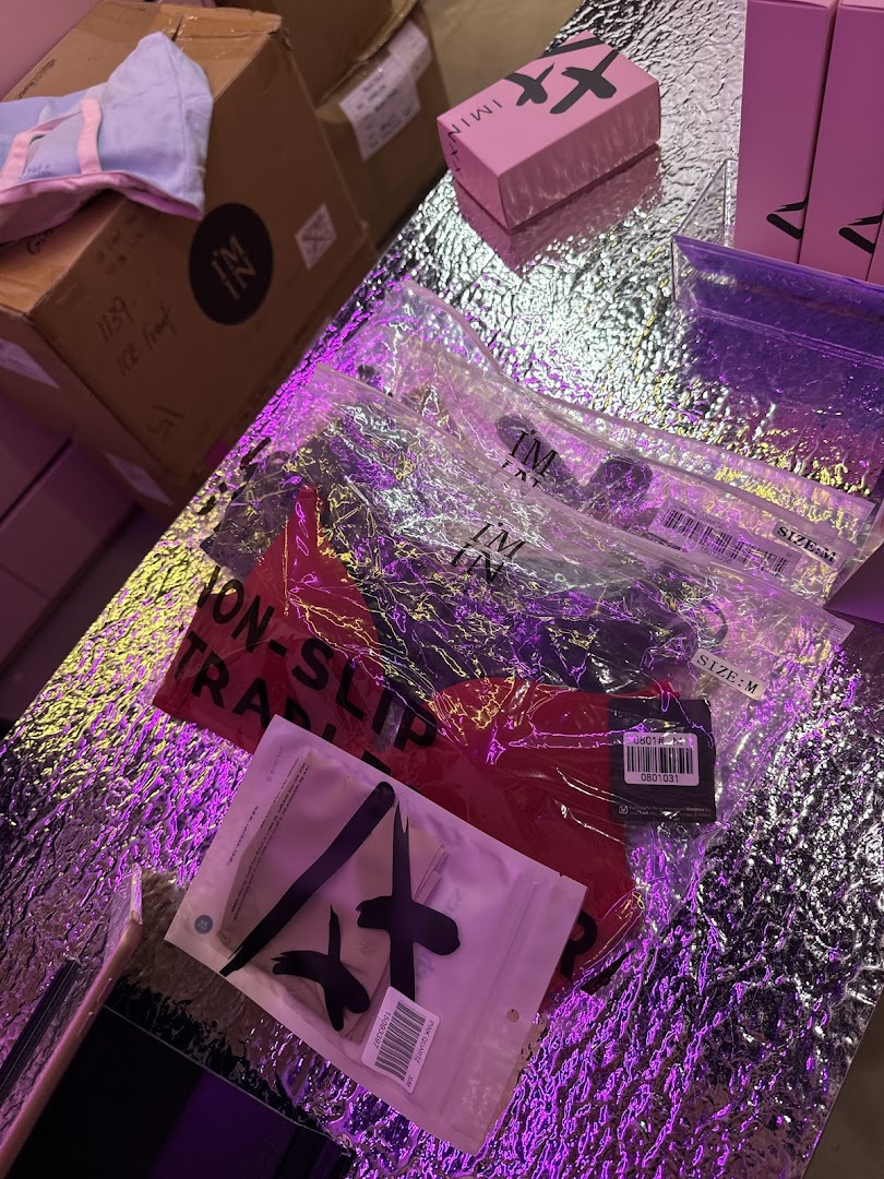 Packaged products from IM IN IMINXX displayed on a reflective surface with vibrant purple lighting.