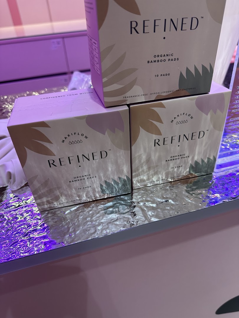 Close-up of REFINED Organic Bamboo Pads boxes displayed on a reflective surface.