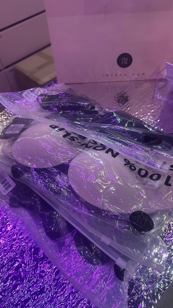 Packaged lingerie accessories, possibly bra inserts, displayed under purple lighting from IM IN IMINXX.