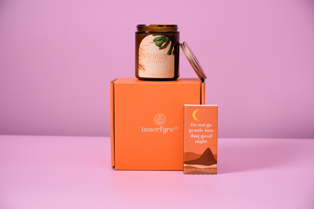 An Innerfyre Co 'Energize Eucalyptus' candle on an orange box with a decorative card.
