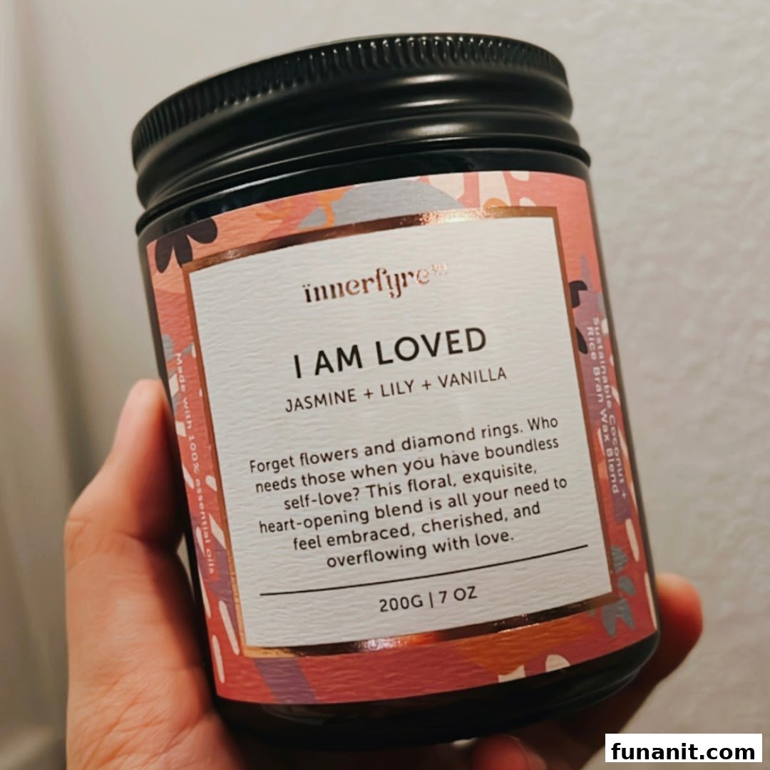 A hand holds an Innerfyre Co. 'I Am Loved' candle jar with jasmine, lily, and vanilla scent.