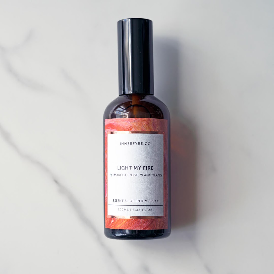 A bottle of Innerfyre Co's 'Light My Fire' essential oil room spray on a marble surface.